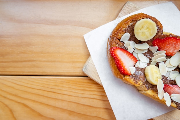 Toasts français avec banane chocolat fraise et amande sur la table en bois