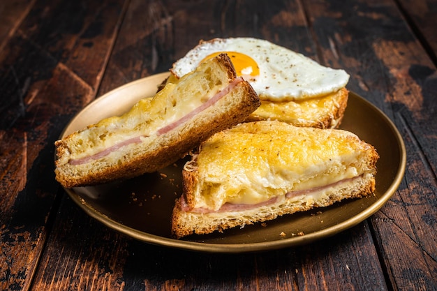 Toasts français Croque monsieur et croque madame sandwichs grillés sur pain brioché avec tranches de jambon fromage emmental fondu et oeuf Fond en bois Vue de dessus