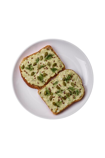 Toasts grillés avec des œufs en pâte d'avocat, du fromage à la crème, des épices et des herbes sur une table en béton texturé