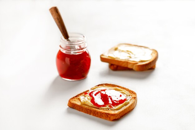 Photo toasts en gros plan avec confiture de fraises et pain et pot sur le tableau blanc