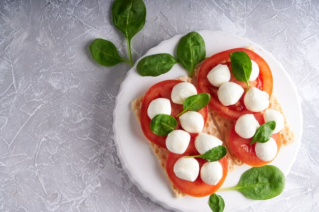 Photo toasts avec mozzarella, tomates et épinards dans une assiette blanche