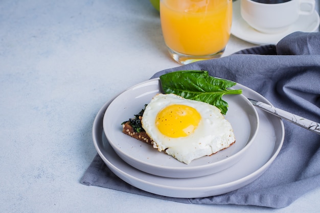 Toasts de pain de seigle avec épinards frits et oeuf sur la table bleue. Concept de nourriture petit déjeuner sain.