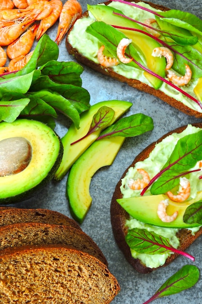 Toasts avec pâte d'avocat, crevettes et blettes. Alimentation équilibrée. Sandwichs ouverts végétariens utiles avec avocat et crevettes. Blettes à salade. Aliments végétariens. Superaliments.