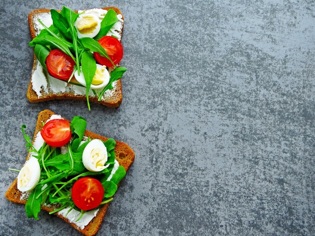 Toasts de seigle de blé avec roquette, œufs de caille et tomates cerises.