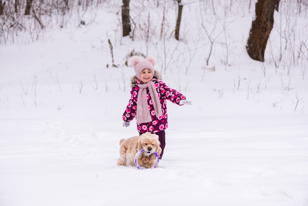 Toddler smiling girl jouer avec un chien en hiver