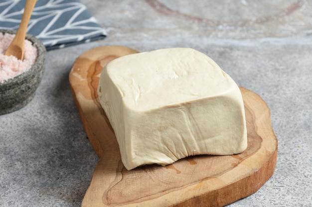 un tofu entier sur planche de bois avec préparation de cuisson au sel de l'himalaya