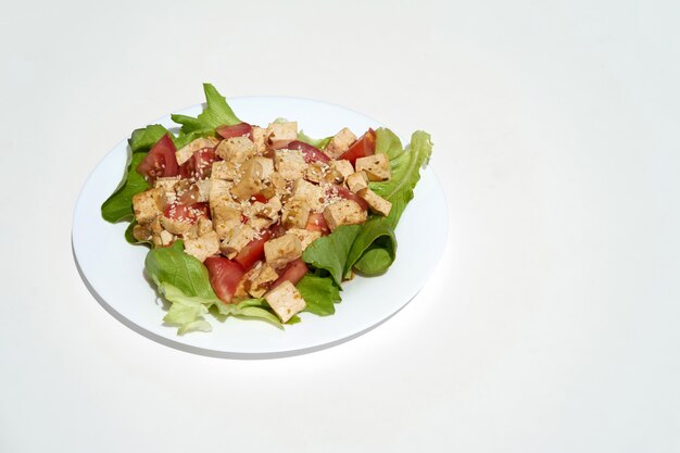 Tofu frit aux légumes et graines de sésame sur plaque blanche