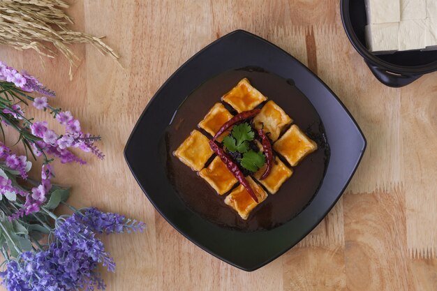 Tofu frit dans un plat noir sur fond en bois