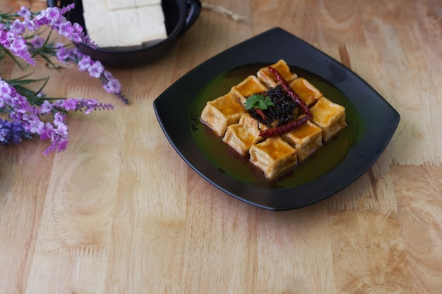 Tofu frit dans un plat noir sur fond en bois