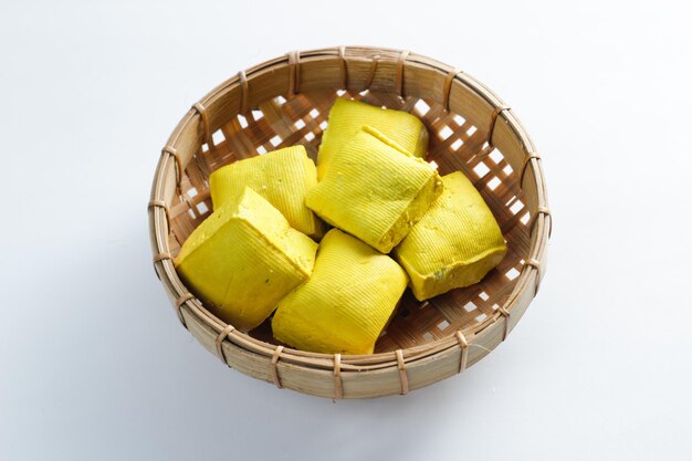 Tofu jaune cru dans un récipient en bambou sur fond blanc Cuisine traditionnelle chinoise