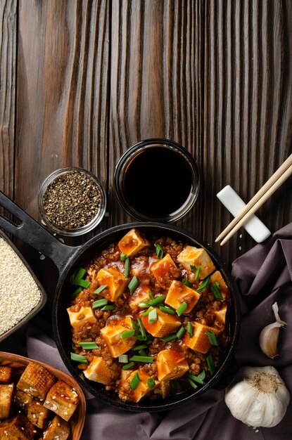 Photo tofu mapo dans une poêle en fonte avec porc ciboulette hachée sauce soja poivre du sichuan ail et épices