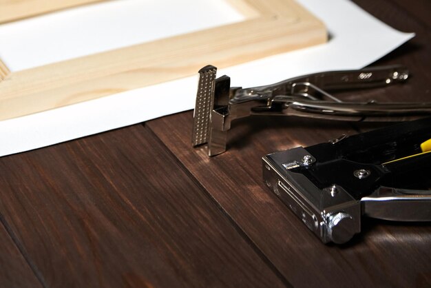 Photo une toile étirée sur une barre d'agrafage en bois et des pinces de toile sur une table brune