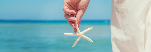 Étoile de mer sur la plage entre les mains d'une femme.