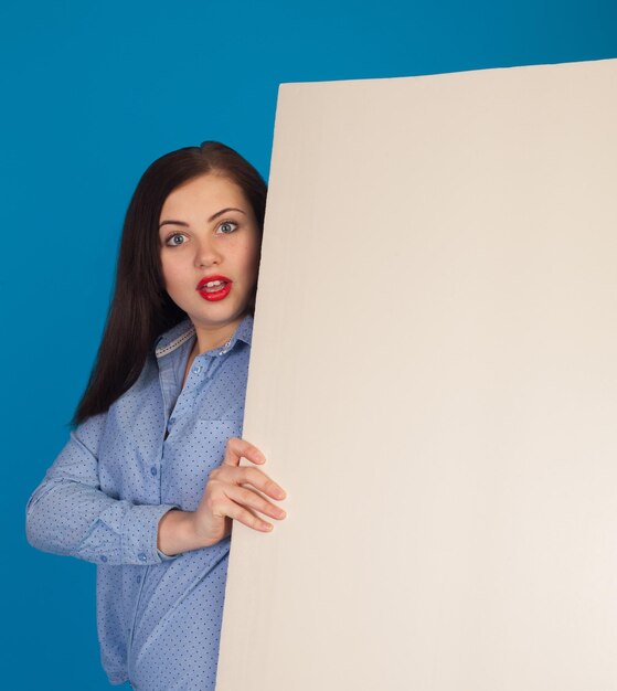 La toile vierge est tenue par une jolie femme aux lèvres rouges sur fond bleu