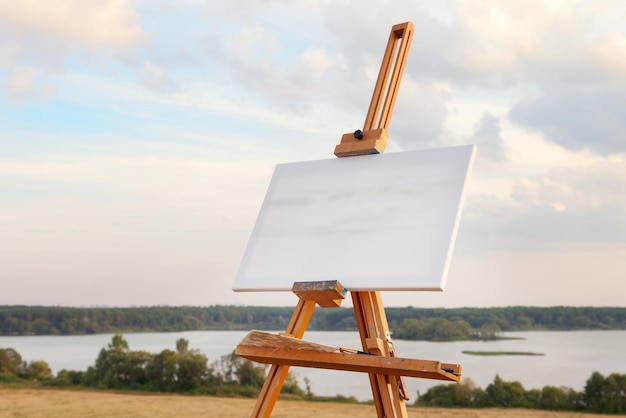 Photo une toile vierge repose sur un chevalet sur un paysage lacustre