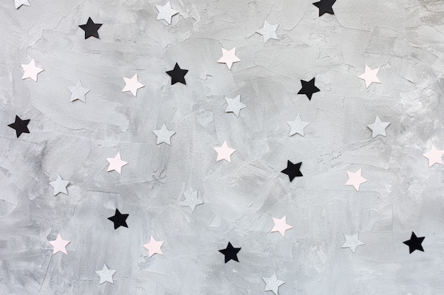 Étoiles de confettis papier tendance sur fond gris.