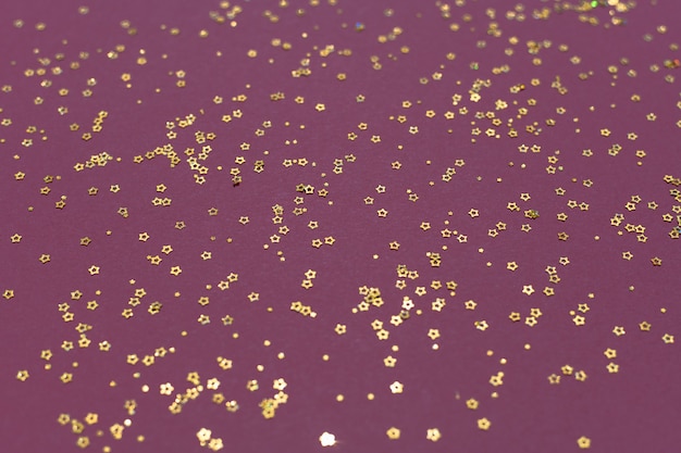 Étoiles de paillettes d'or sur fond violet