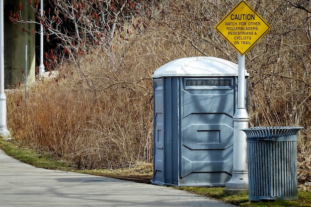 Toilette portable et poubelle à déchets avec panneau sur le bord de la route