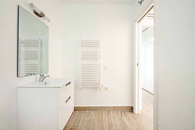 Toilettes blanches avec carrelage aspect bois, radiateur mural et miroir