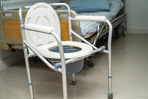 Toilettes à chasse d'eau et chaise de douche dans la salle de bain pour personnes âgées