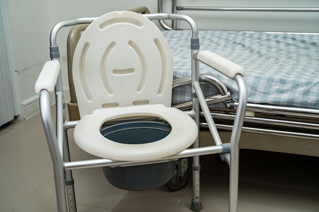 Toilettes à chasse d'eau et chaise de douche dans la salle de bain pour personnes âgées