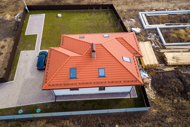 Toit en bardeaux métalliques maison avec fenêtres grenier et voiture noire.