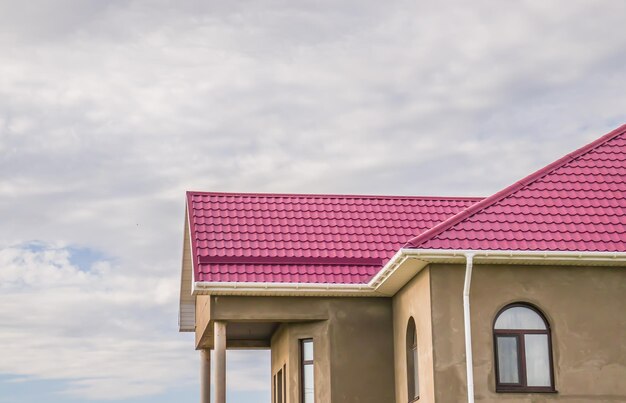 Photo le toit est en métal, des feuilles de toiture métalliques, des matériaux de toiture modernes, des carreaux métalliques sur le toit de la maison contre le ciel bleu.