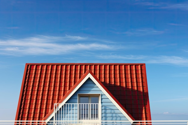 Un toit rouge surmonté d'une maison bleue