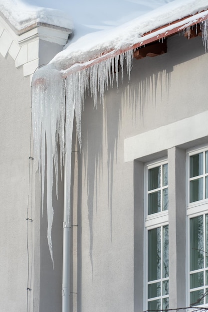 Les toits des bâtiments sont recouverts de neige et de glace après une grosse chute de neige D'énormes glaçons pendent des façades des bâtiments La chute de glaçons met en danger la vie des gens