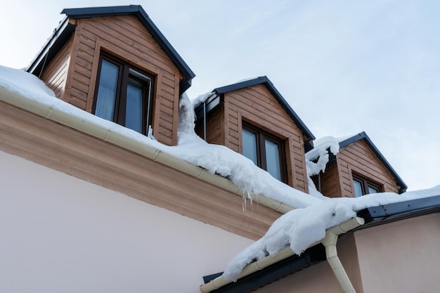 Les toits des bâtiments sont recouverts de neige et de glace après une grosse chute de neige D'énormes glaçons pendent des façades des bâtiments La chute de glaçons met en danger la vie des gens