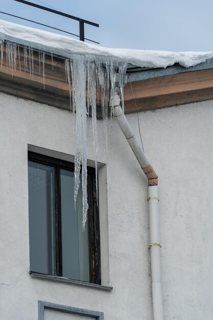 Les toits des bâtiments sont recouverts de neige et de glace après une grosse chute de neige D'énormes glaçons pendent des façades des bâtiments La chute de glaçons met en danger la vie des gens