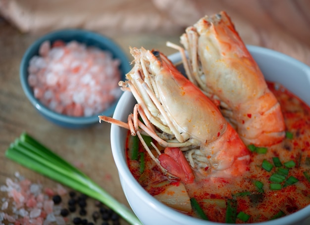 Tom Yum Kung et condiments sur table en bois