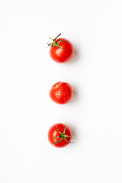 Tomate cerise fraîche sur fond blanc, pose à plat.