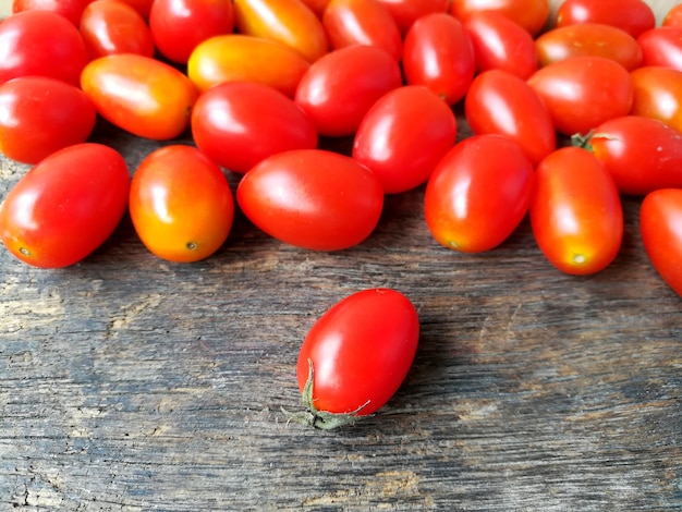 Une tomate cerise rouge devant les pièces l&#39;autre sur le fond en bois