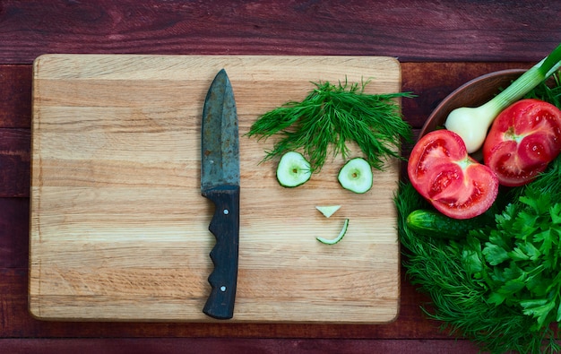 Tomate, concombre, oignon, persil et aneth sur une surface en bois