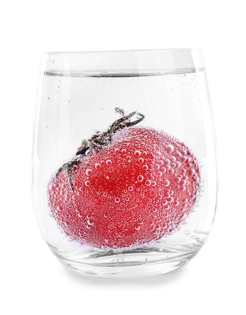 Tomate dans un verre d'eau isolée sur blanc