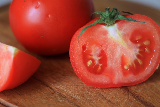 Une tomate est sur une planche à découper avec une tige verte.