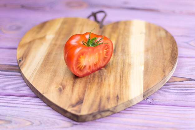 Tomate fraîche sur un fond en bois sous forme de coeur
