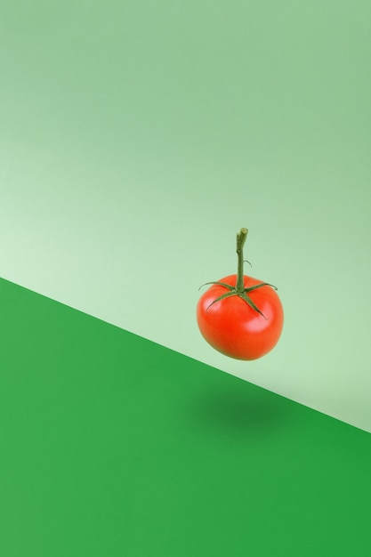 Tomate de légumes verts frais flottant sur un fond géométrique vert, régime vitaminé végétarien et végétalien équilibrant le concept de nourriture créative, espace de copie, régime sain d'alkakine