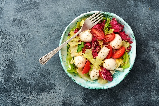 tomate mozzarella et mélange de feuilles de salade fraîches table en pierre d'ardoise