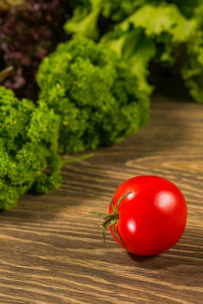 Tomate mûre juteuse sur une table en bois avec une salade verte en arrière-plan Légumes frais Délicieuse salade végétarienne