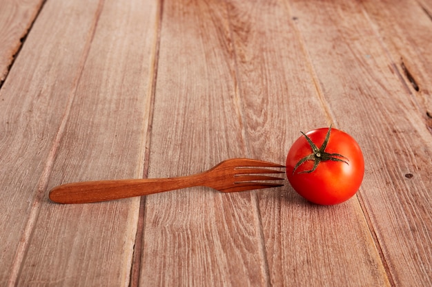 Une tomate mûre sur une planche décorative.