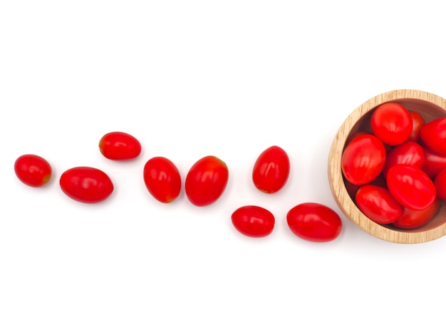 Tomate de raisin ou de cerise fraîche dans un bol en bois sur fond blanc.