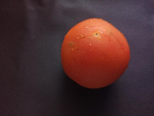 Photo une tomate rouge est sur un tissu noir.