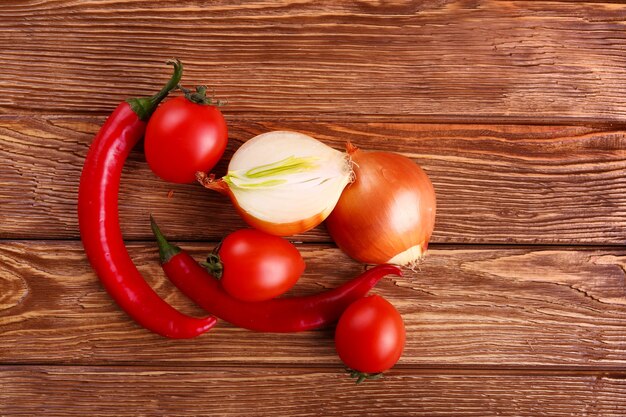 Tomate rouge fraîche, piment et oignon dans une table en bois