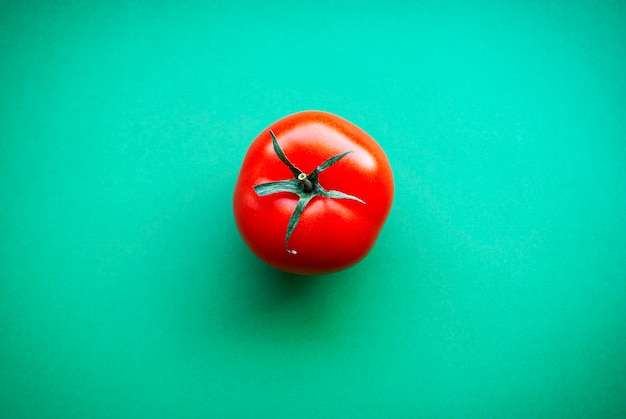 Une tomate rouge sur une surface verte.