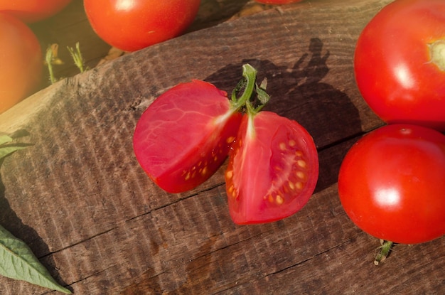 Tomate avec tranche sur fond de bois rustique Tomate fraîche coupée sur table en bois