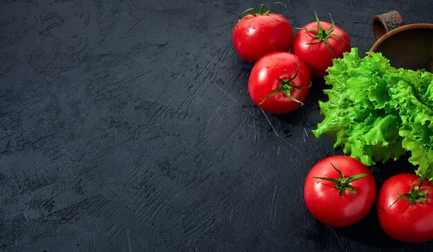 Tomates aux feuilles de salade sur fond de pierre noire.