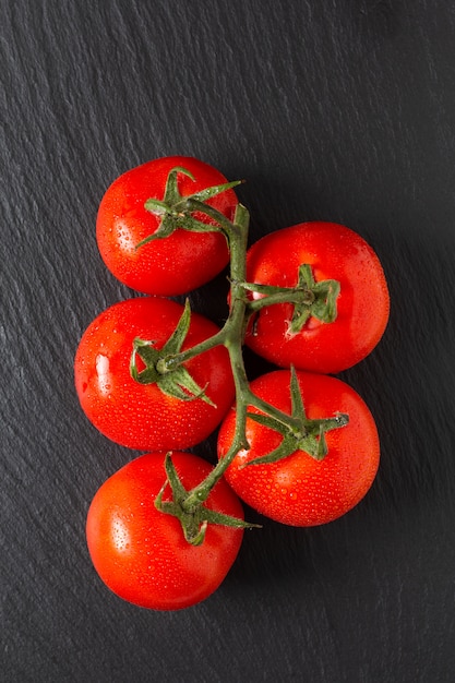 Tomates biologiques de concept alimentaire sur ardoise noire avec espace de copie