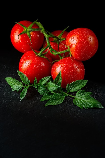 Tomates biologiques mûres sur le tableau noir en discret avec des gouttes d'eau
